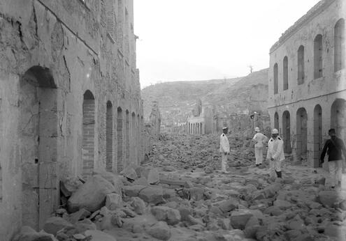 Several men walking among the ruins and rubble on Rue Victor Hugo