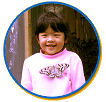 A butterfly that's landed on the chest of a smiling child.
