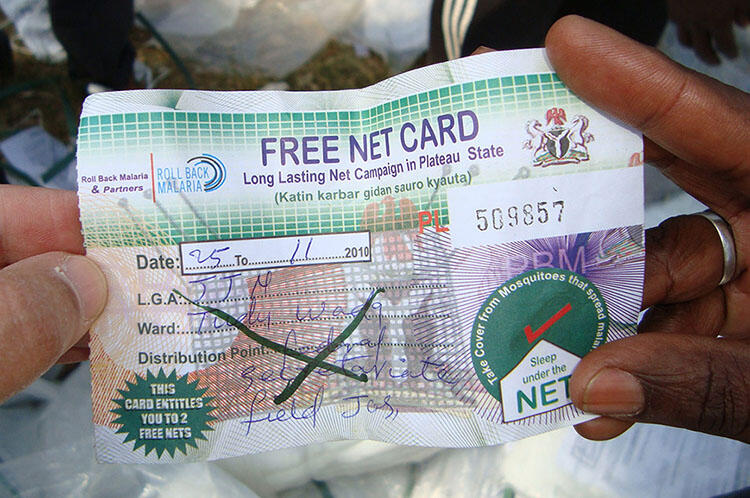 Two hands hold a piece of paper with text "Free Net Card" at the top, space to write the date and distribution point and colorful background designs.