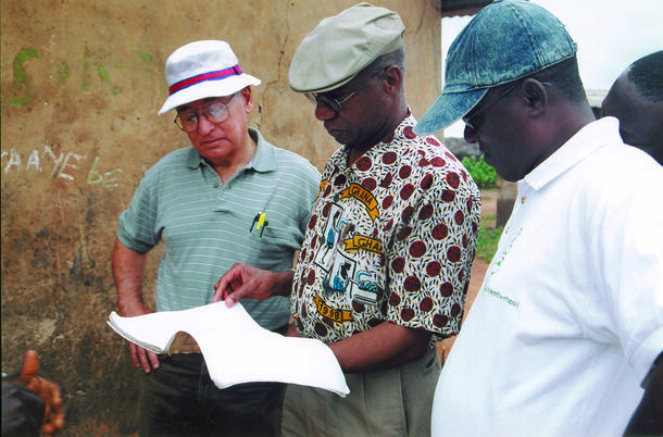 Dr. Donald R. Hopkins, Dr. Ernesto Ruiz-Tiben and Dr. Andrew Seidu Korkor stand and look at a local case logbook.
