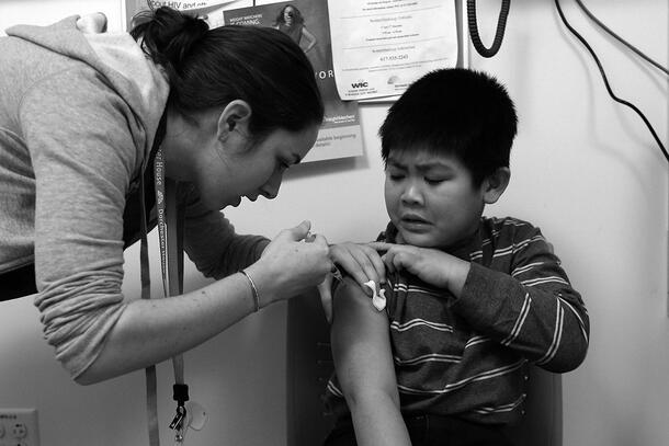 A child receives a vaccination via needle from a doctor.