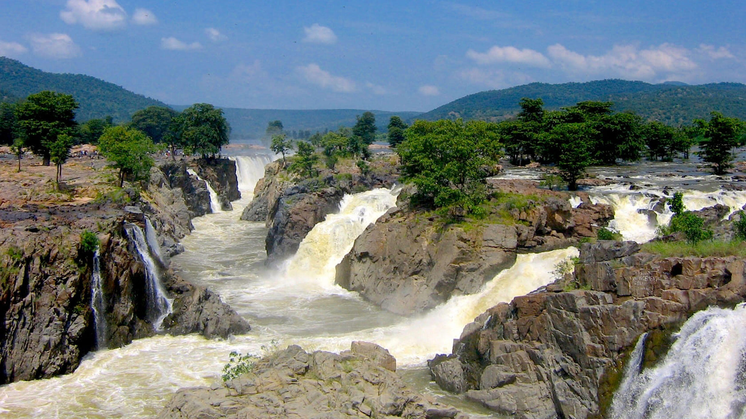 Multiple waterfalls pour into a river below at the Hogenakkal Waterfalls in India.