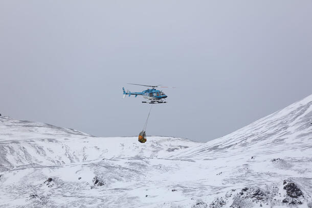 Helicopter flies over icy peaks in Antarctica.