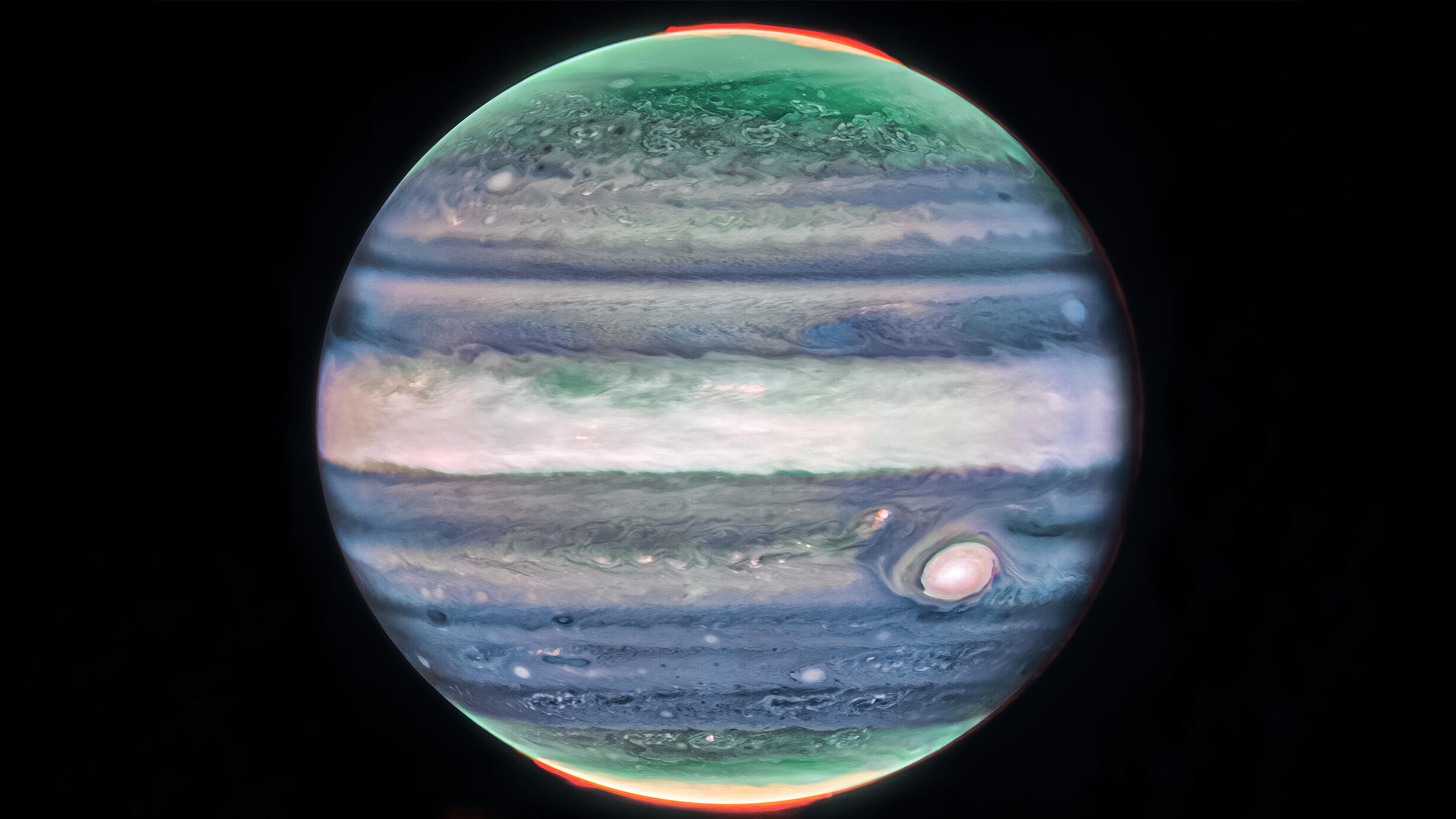 The planet Jupiter, with multicolored striped bands running across its surface, against a dark background.