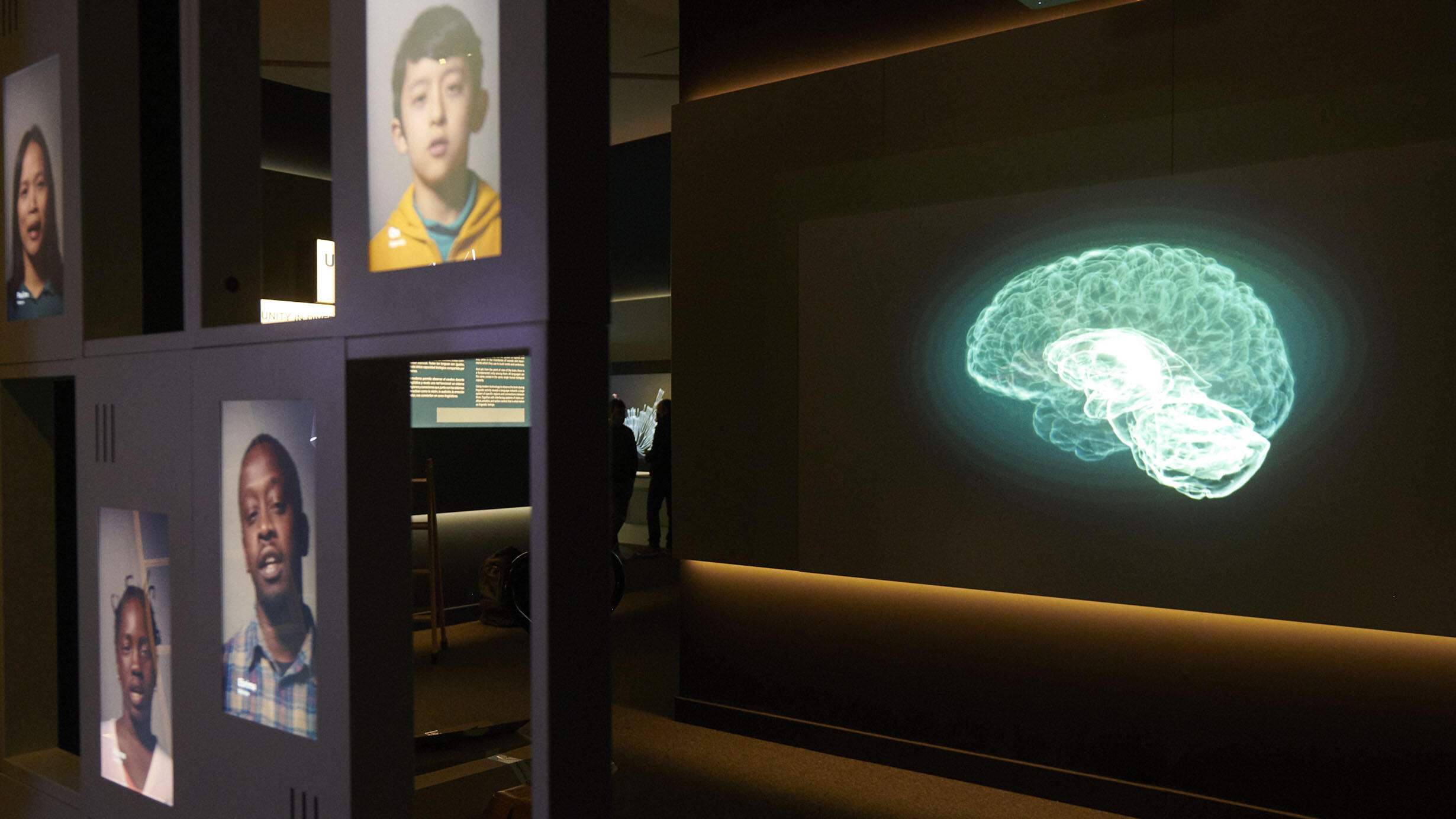 A screen displaying a digital image of a brain is juxtaposed next to a panel showing a collage of different faces.
