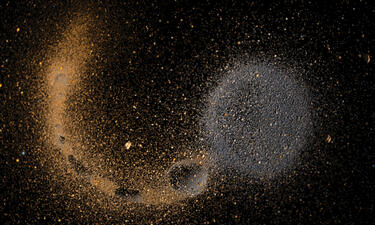Millions of tiny grey and brown particles begin to combine into one large mass