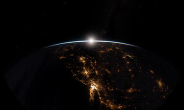 La Tierra mostrada desde el espacio en la noche con ciudades brillando. 