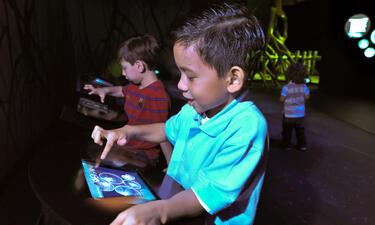A boy smiling and touching an iPad screen
