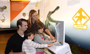 A family surrounds a touchable exhibit of an eagle's leg and talons