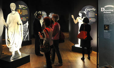 Visitors walk through graphic cut-out displays of famous figures from history including Napoleon and Cleopatra