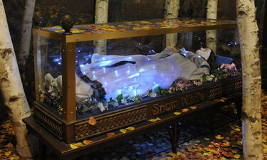 A life-size diorama shows a model of Snow White sleeping in a glass coffin in a forest