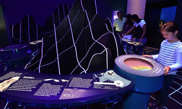 A girl examines a model of a recreated map of the seafloor topography