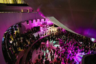 Very large standing crowd gathers in the dramatically-lit Cullman Hall of the Universe.