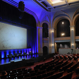 Rows of empty velvet seats face a giant screen inside the Museum's ornately-designed Lefrak theater.
