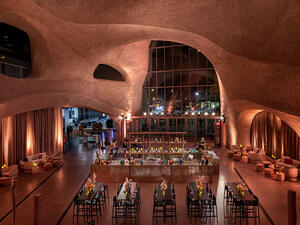 A horseshoe-shaped bar next to high tables and chairs and lounge areas are set up inside the Museum's Gilder Center Atrium.