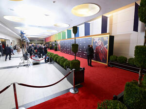 A red carpet lined by stanchions and artificial trees and plants lines the entrance hall inside the Museum's Rose Center.