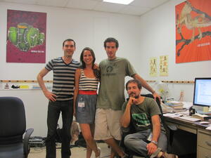 Four people posing for the camera in a office with posters of reptiles and amphibians on the walls, and a desk with a computer, books, and paperwork.