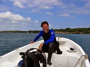 A man on a small boat wearing a wetsuit.