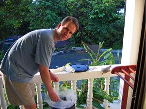 A man outdoors on a porch working with materials.