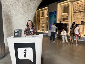 A Museum volunteer sits behind an information desk in the Gilder Center atrium.