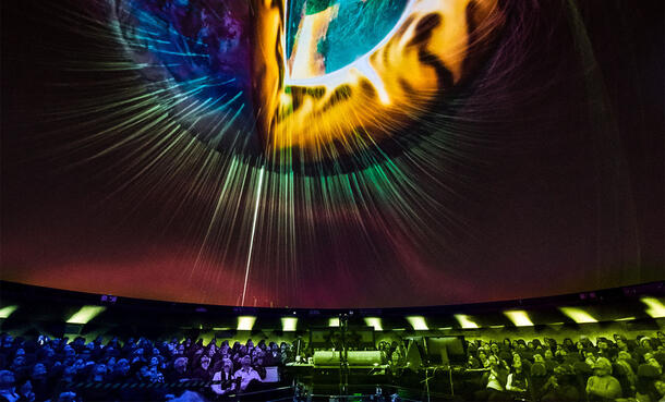 Seated visitors view an overhead screen projecting images from space inside the Museum's Hayden Planetarium.