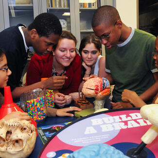 Six students gather around models in the lab.