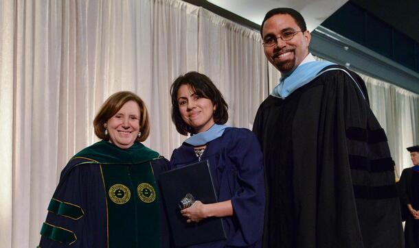 Two students wearing caps and gowns participate in the MAT graduation ceremony.