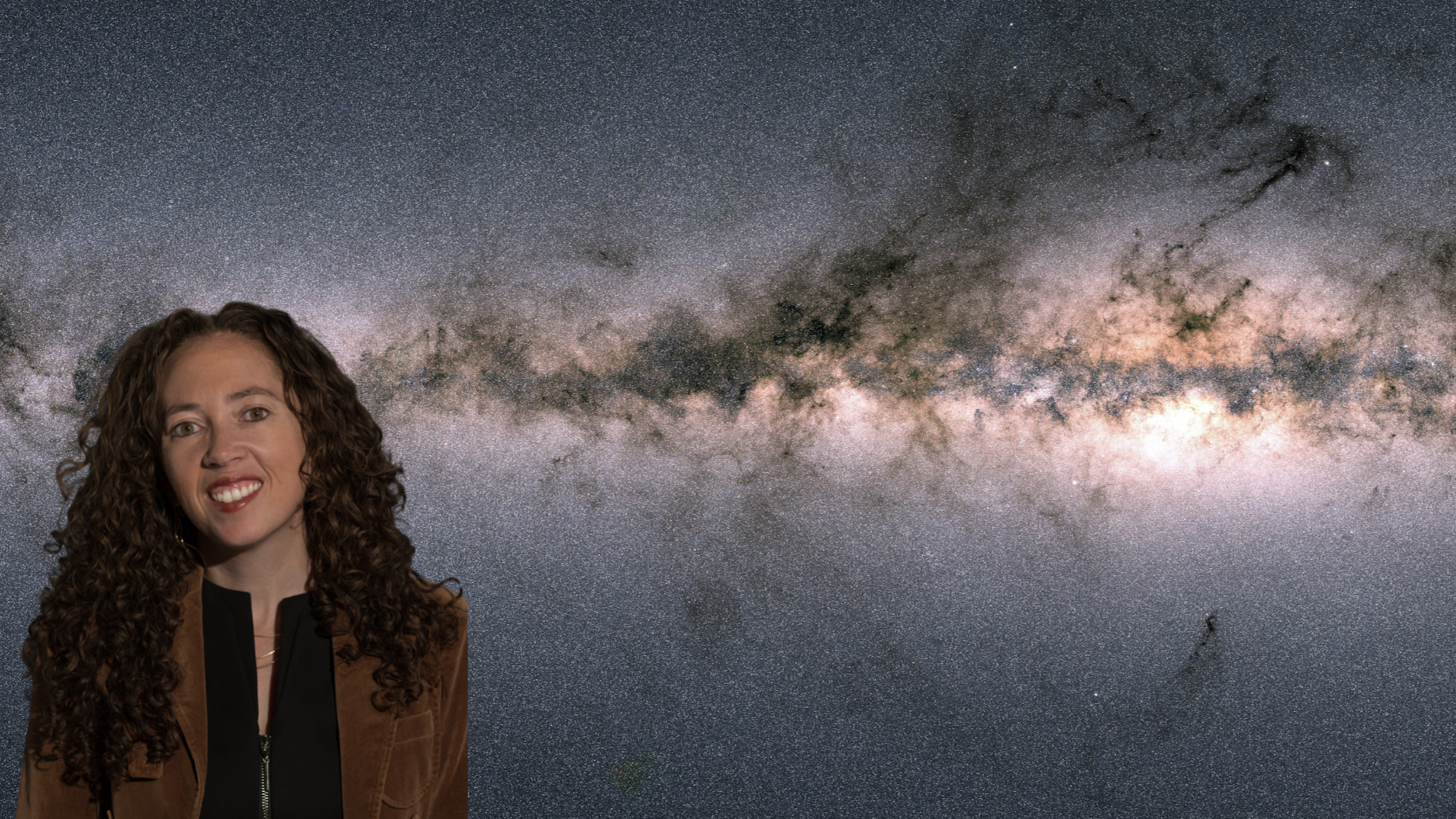 A woman with curly brown hair stands in front of an image of the Milky Way