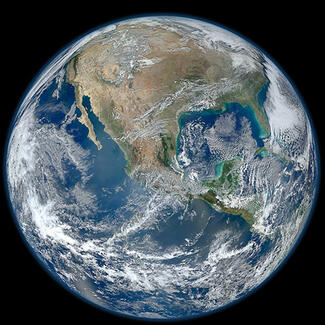 View of Planet Earth from space with a view of most of North America, with streaks of clouds over the Pacific Ocean and Central America.