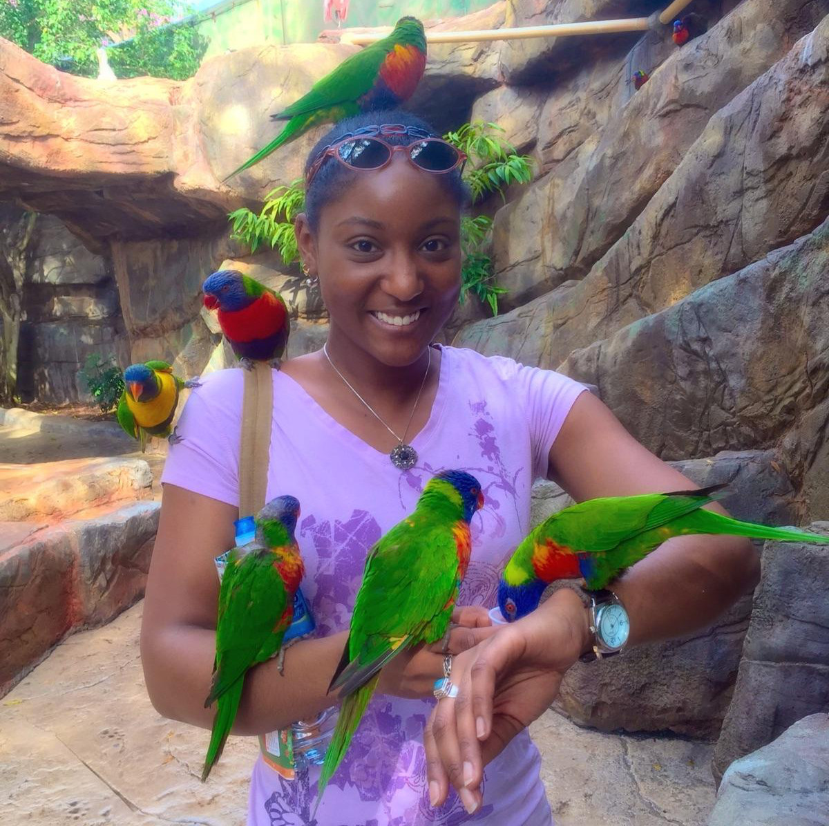 photo of Jessica Andre standing holding birds and with birds resting on her body