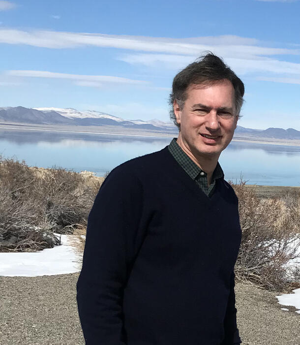 Dr. Robert Steiner, faculty of the Master's in Arts of Teaching program lakeside with mountains in the distance.