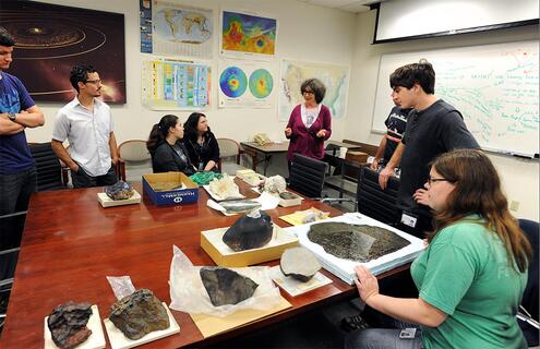 Teacher and students observing various rock specimens in a classroom