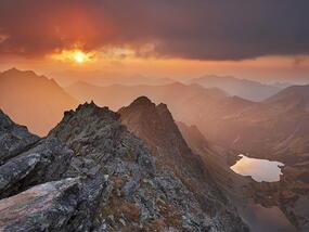 a mountain landscape with a sunset happening in the background