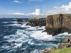 the ocean meets tall coastal cliffs