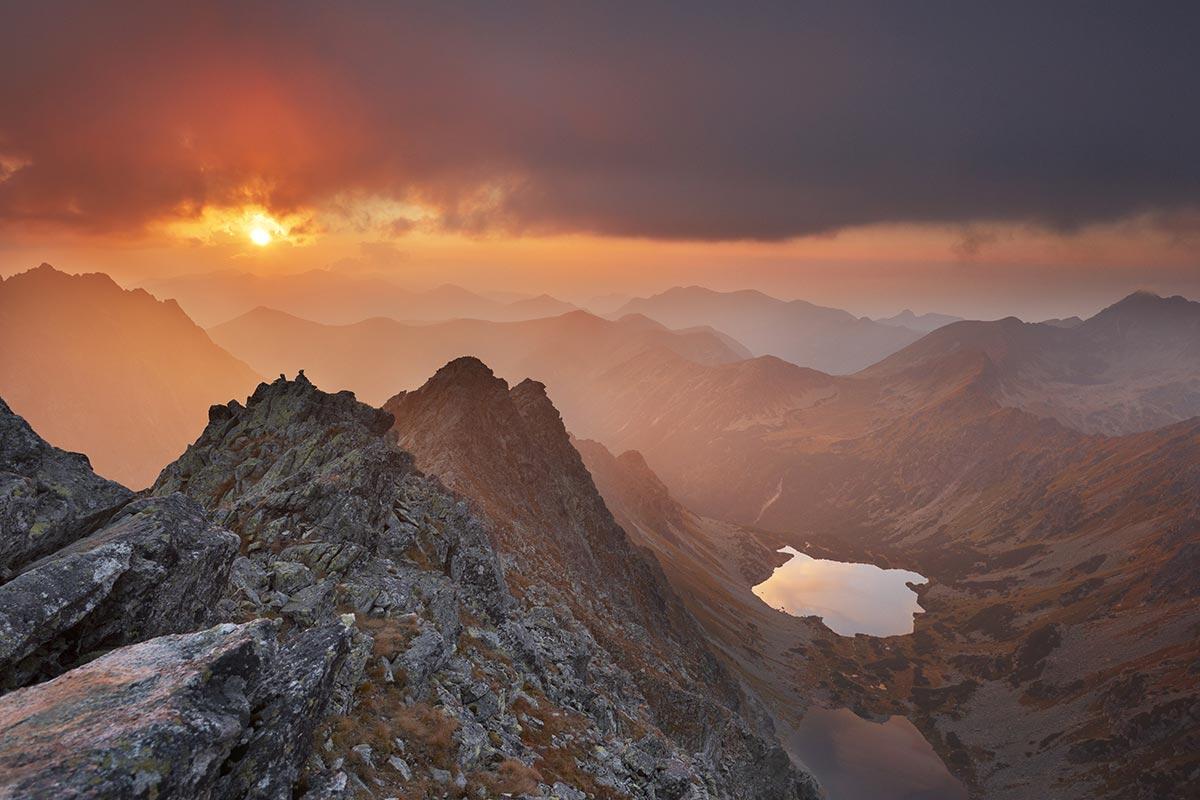 a mountain landscape with a sunset happening in the background