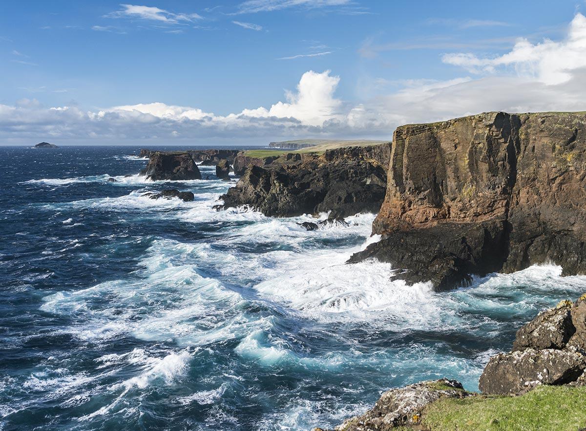 the ocean meets tall coastal cliffs