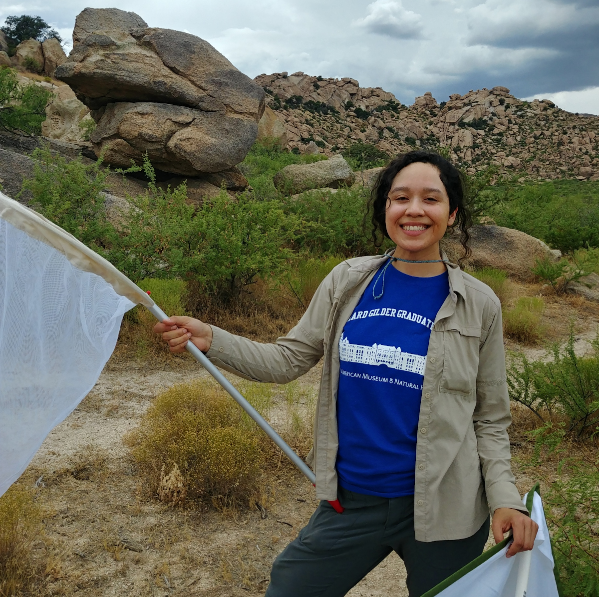 Nayeli Gutierrez standing among a large rock formation holding a large net