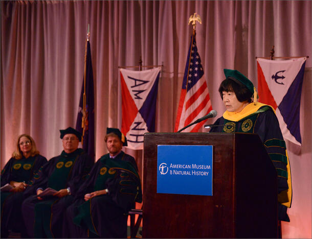 Speaker at a podium during a graduate school commencement ceremony at the Museum