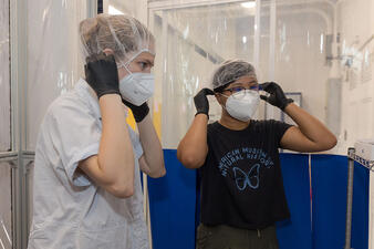 Two lab users put on masks to prepare to enter the AbLab.