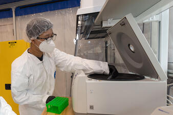 Researcher inside the abLab places a specimen inside a centrifuge.