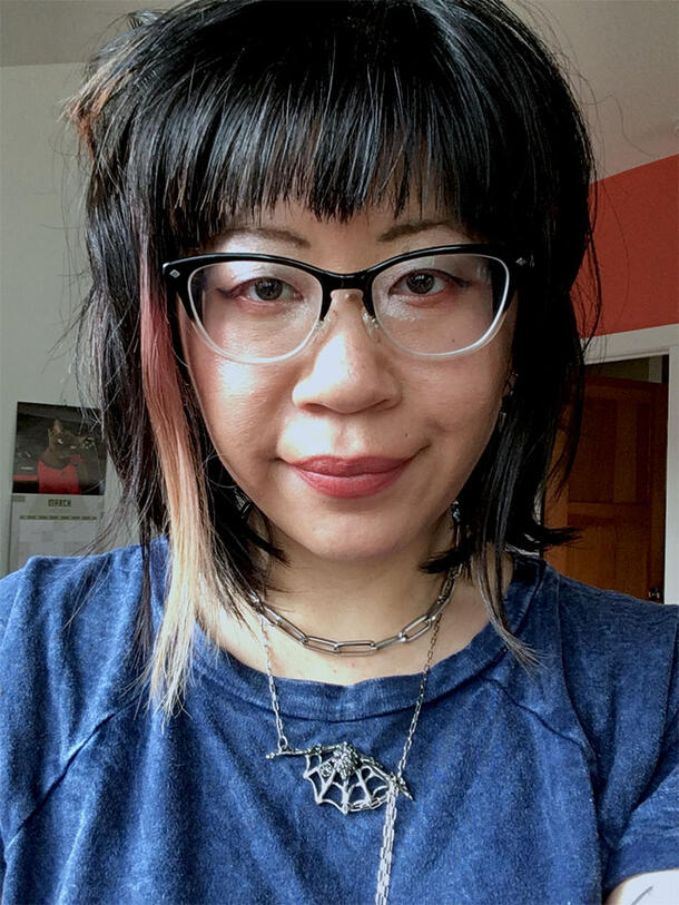 Headshot of Audrey Lin wearing a spiderweb necklace and smiling gently.