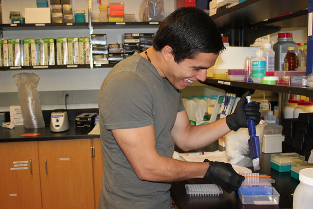 Student practices pipetting in a lab. 