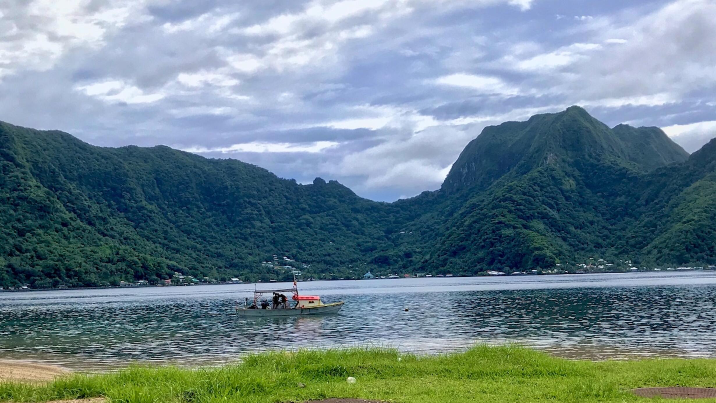 A boat in the water with mountains in the backgrounds in the American Samoas