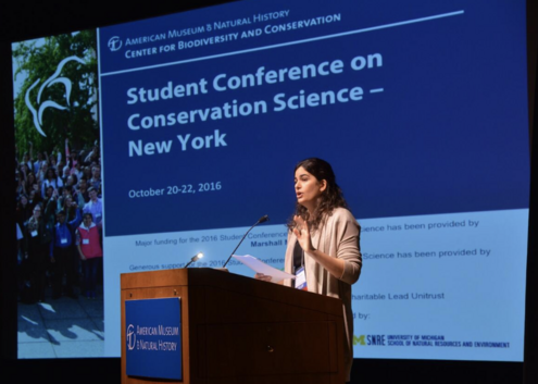 A woman stands at a podium and speaks.