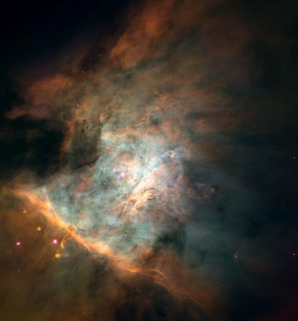 Multicolored Orion nebula glowing against dark space.