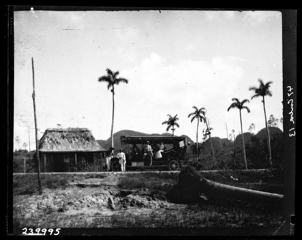 Black and white photograph of a stage coach from Pinar del Rio with a bride climbing aboard in Vinales, Cuba