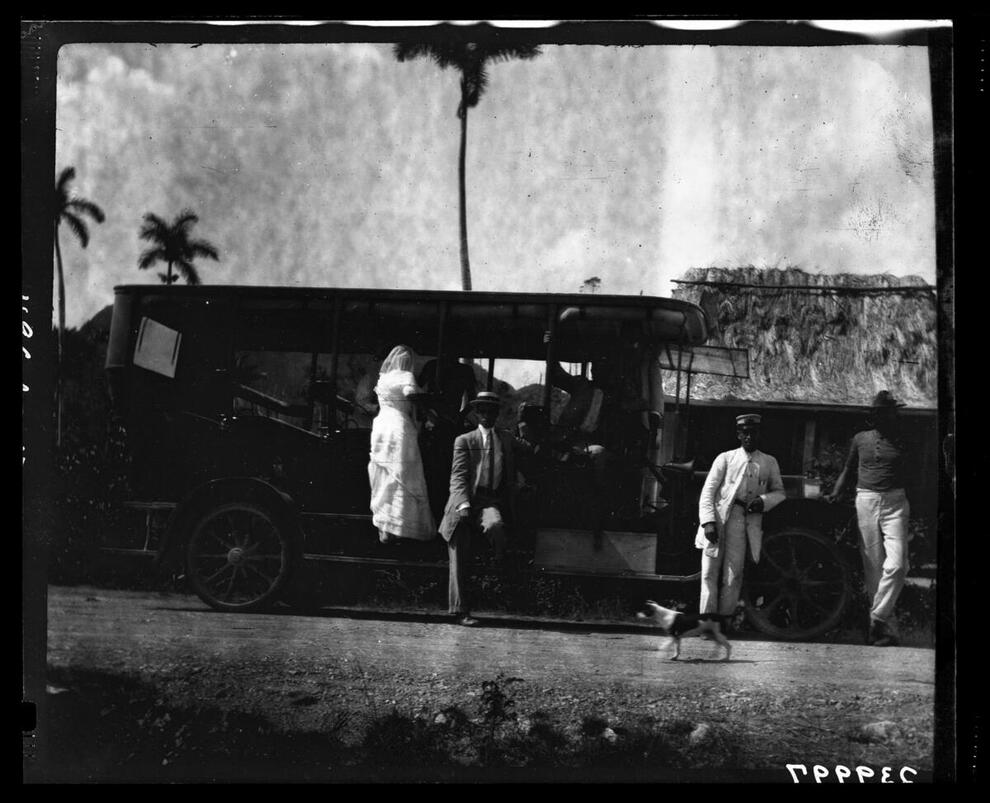 Black and white photograph of a stage coach from Pinar del Rio with a bride climbing aboard in Vinales, Cuba.