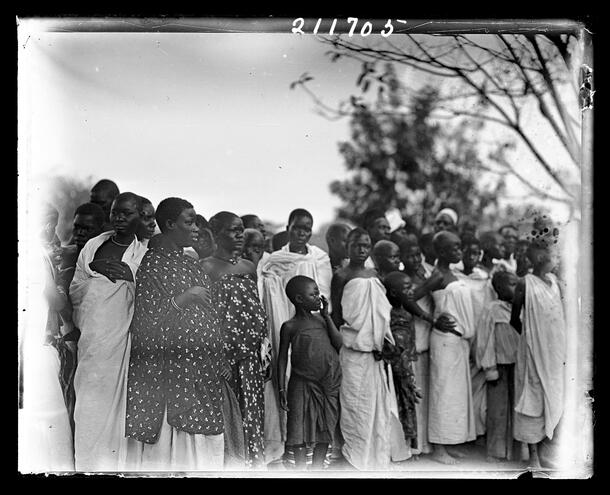Women and children observing a game day in Masindi, Uganda; taken during the Akeley Expedition to British East Africa (1909-1911).