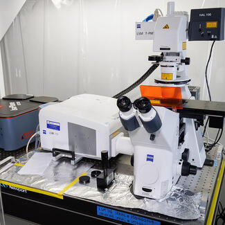 Zeiss LSM 710 microscope sits on a lab table surrounded by plastic curtains.