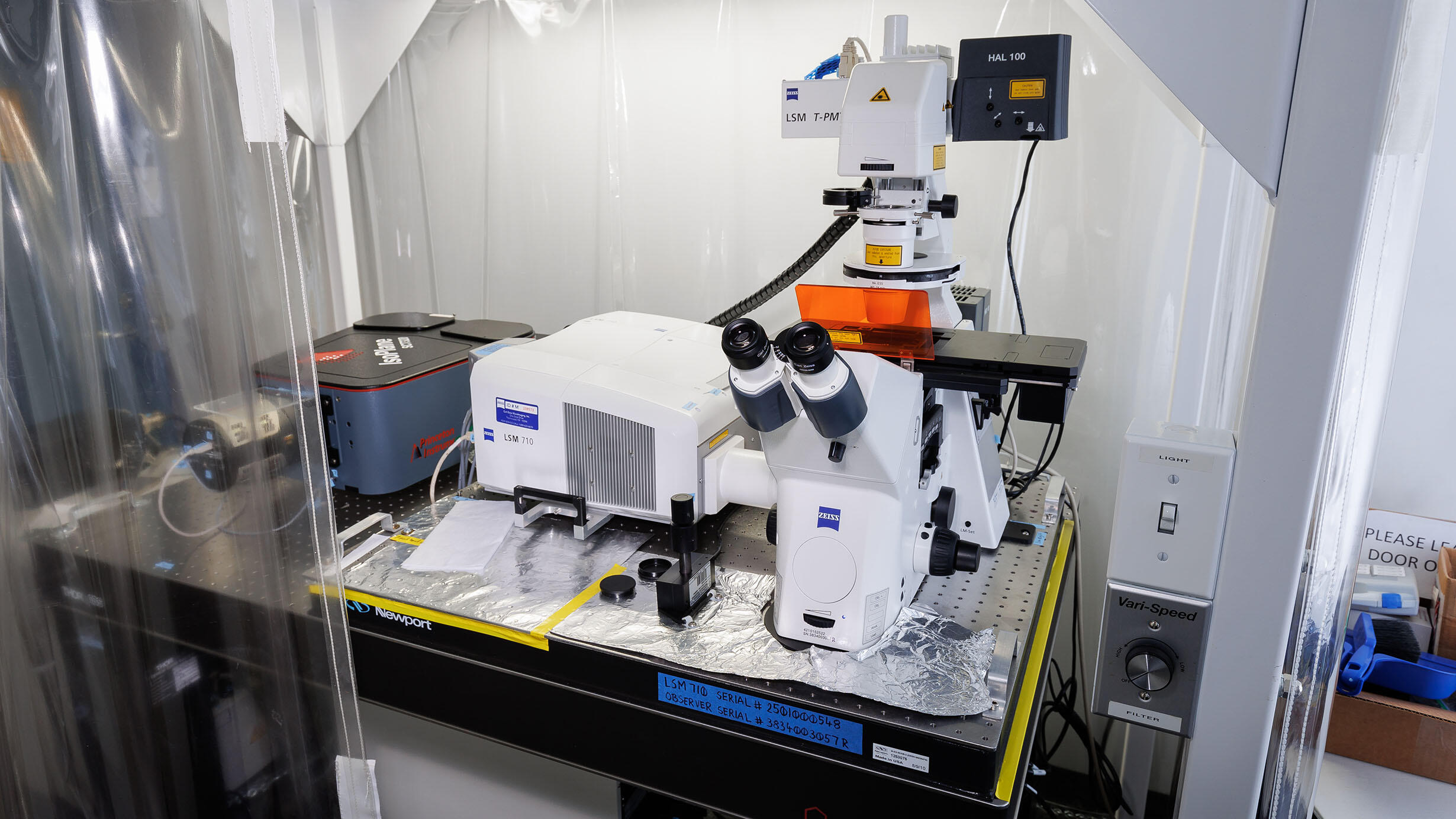 Zeiss LSM 710 microscope sits on a lab table surrounded by plastic curtains.